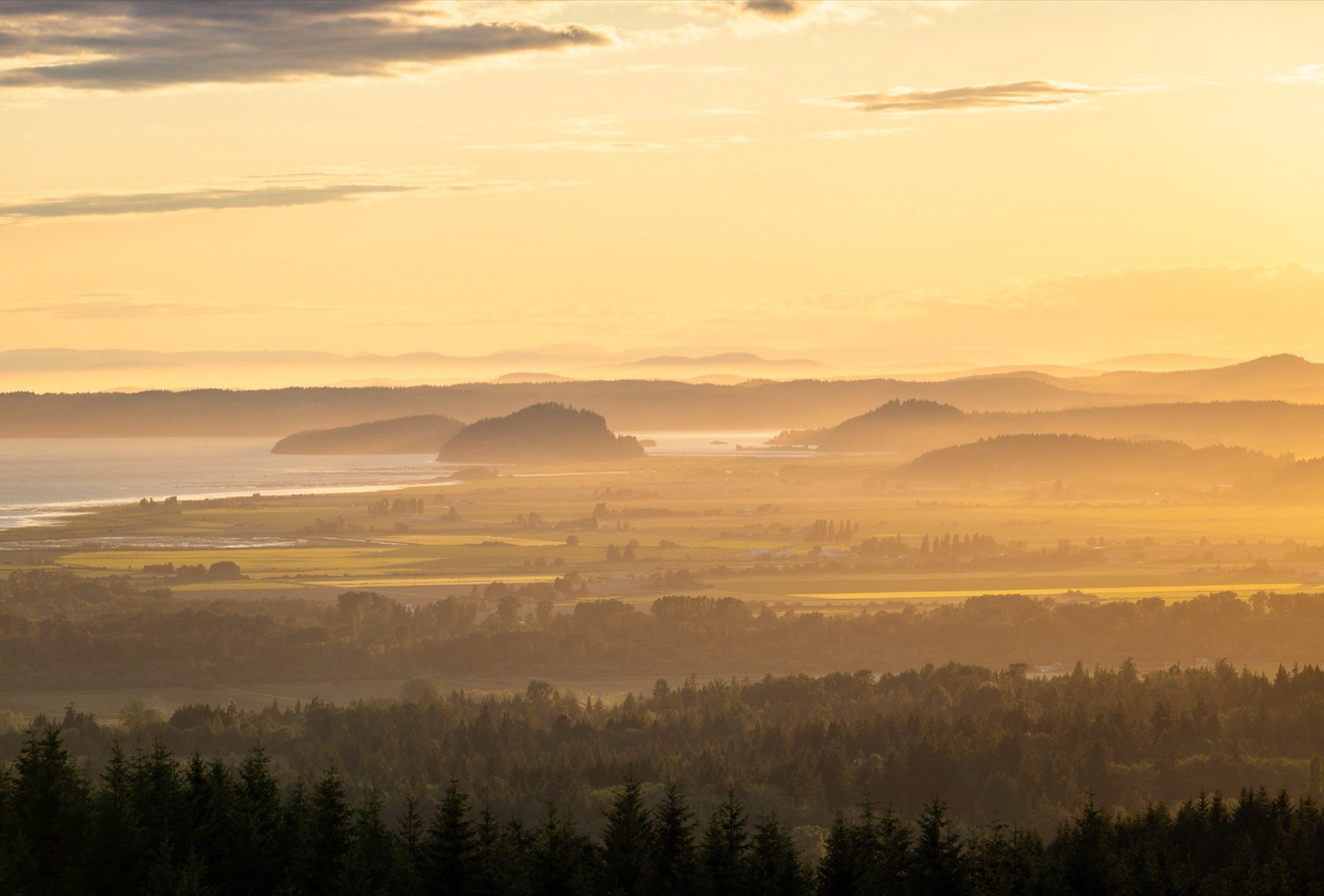 A wide valley at sunset under a warm, hazy sky